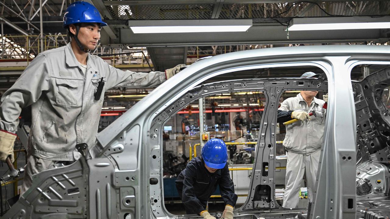 Employees work on an electric vehicle. China has become a powerhouse of EV production. Picture: AFP