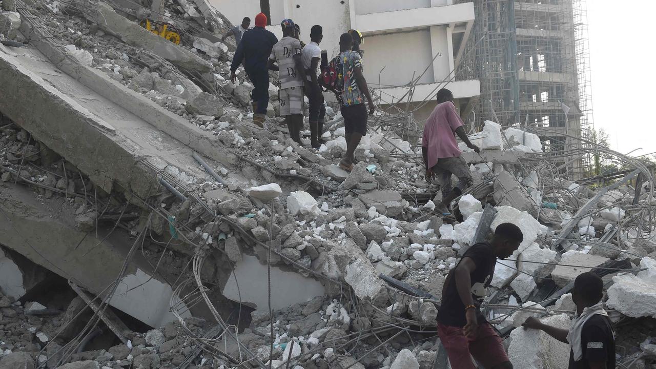 People walk to rescue workers from the rubble of a building under construction that collapsed at Ikoyi district of Lagos.