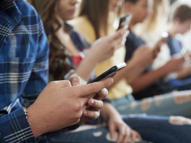 Close Up Of A Line Of High School Students Using Mobile Phones