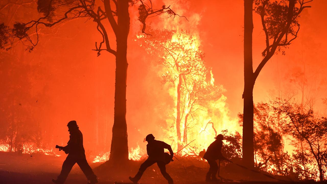 RFS volunteers and NSW Fire and Rescue officers fight a bushfire encroaching on properties near Termeil on the Princes Highway between Batemans Bay and Ulladulla on Tuesday. Picture: AAP Image/Dean Lewins.