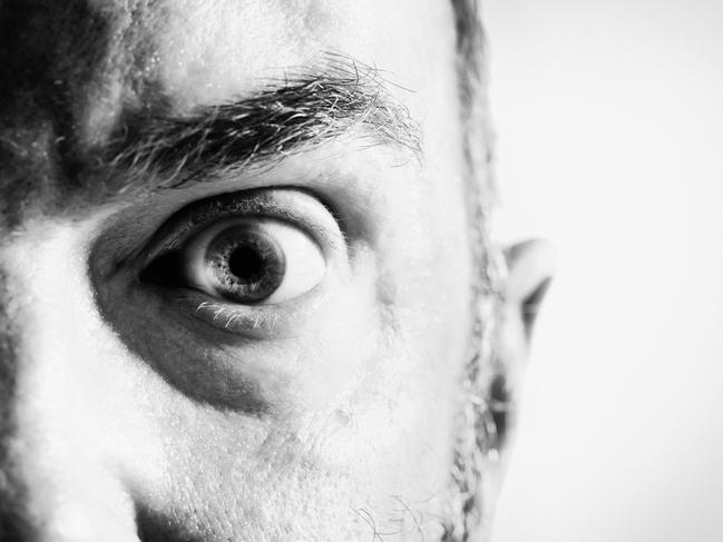 Black and white, cropped portrait of a startled mature man frowning and looking irritated.