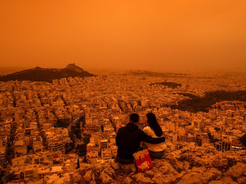 A couple sits on Tourkovounia hill, as southerly winds carry waves of Saharan dust, in Athens, on April 23, 2024. Clouds of dust blown in from the Sahara covered Athens and other Greek cities on April 23, 2024, one of the worst such episodes to hit the country since 2018, officials said. Picture: AFP