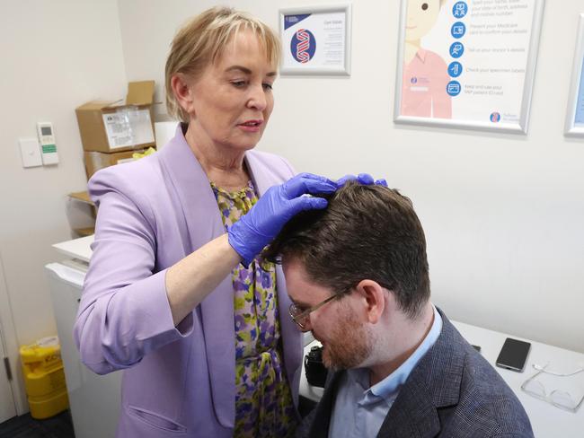 Ros Bates Shadow Minister for Health and Ambulance Services medically assisting journalist Andrew Messenger who split his head open on his way to a media conference, The Family Practice Emu Park. Picture: Liam Kidston.