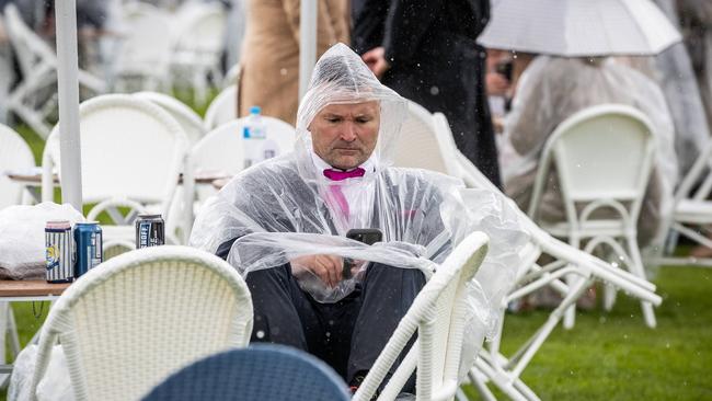 HAVING FUN: A man is seen wearing a poncho while sitting alone. Picture: Jake Nowakowski