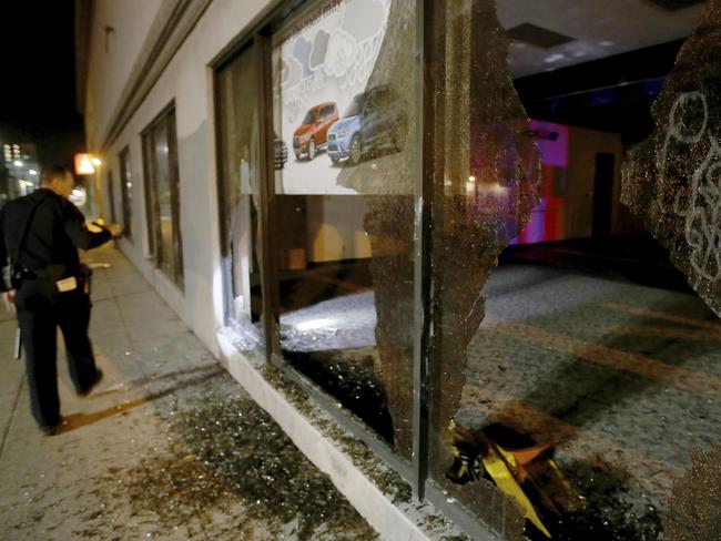 An Oakland police officer checks out damage after a window was broken by protesters. Picture: Jane Tyska/Bay Area News Group via AP