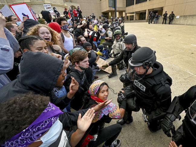 Law enforcement officers take the knee and shake hands with protesters to cheers from the crowd. Picture: AP