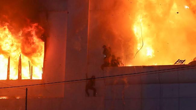 At least 19 people have died in a fire at a Cambodian hotel-casino on the border of Thailand, with photos showing groups desperately huddled on ledges as fierce flames surround them. Picture: AFP.