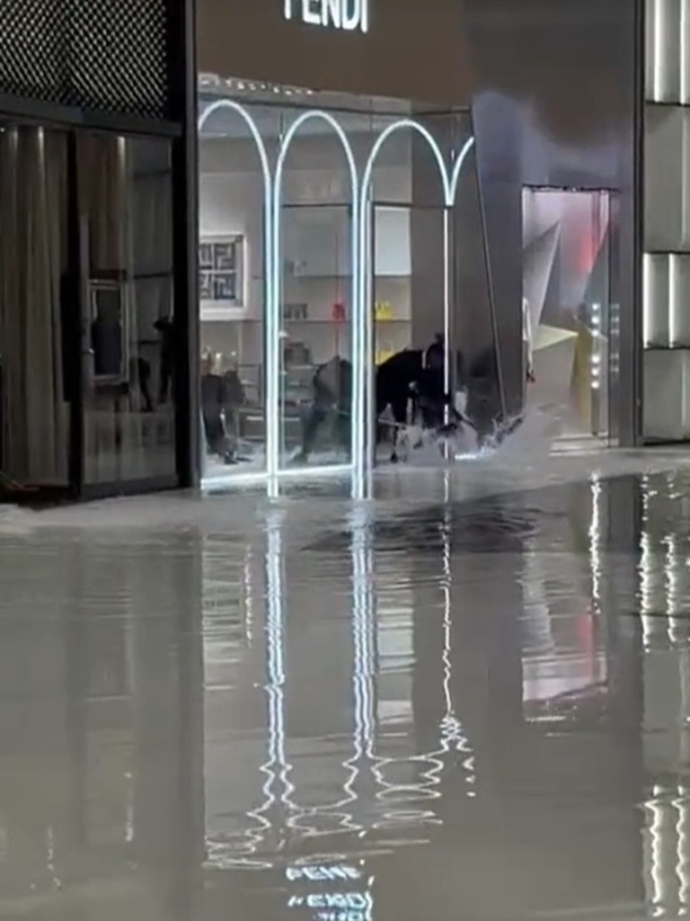 Staff can be seen trying to sweep out water from luxury stores such as Fendi and Chanel.