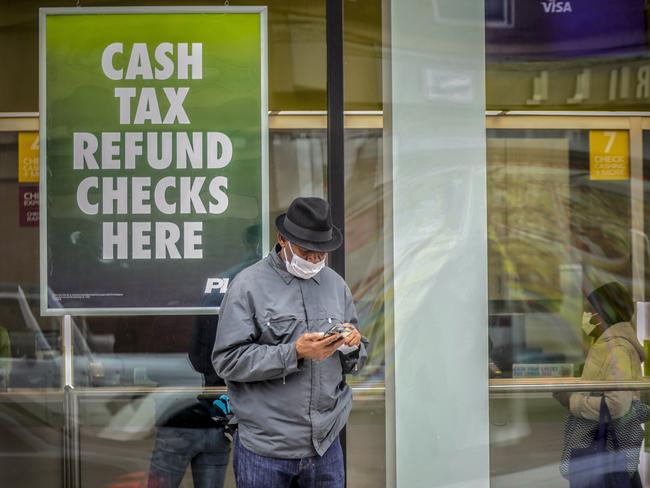 A man wears a face mask as he stands outside a cheque cashing service centre in the Brooklyn borough of New York. Picture: AP