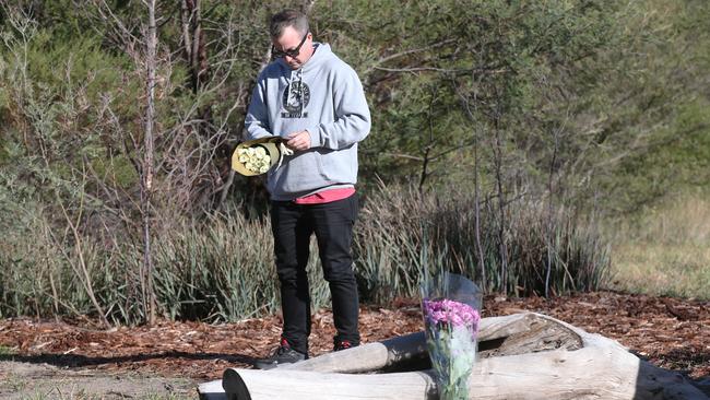 A man places flowers at the scene in Royal Park where the body of a woman was found. Picture: David Crosling