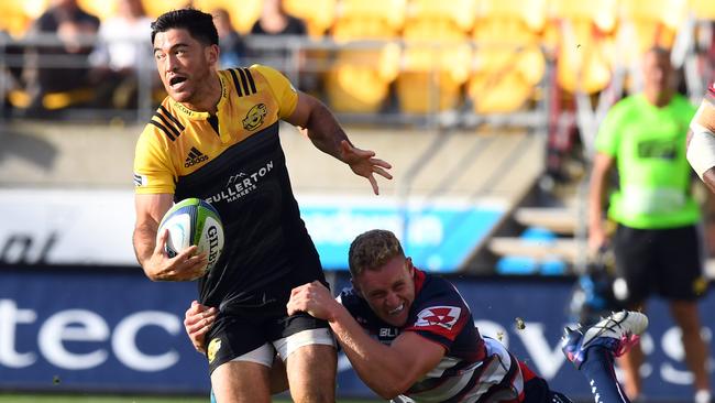 Nehe Milner-Skudder of the Hurricanes is tackled by Reece Hodge of the Rebels.