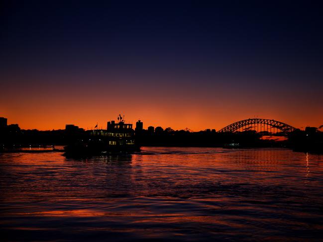 The sun rises over Sydney as a ferry pulls out of Balmain wharf. Picture Cameron Richardson.