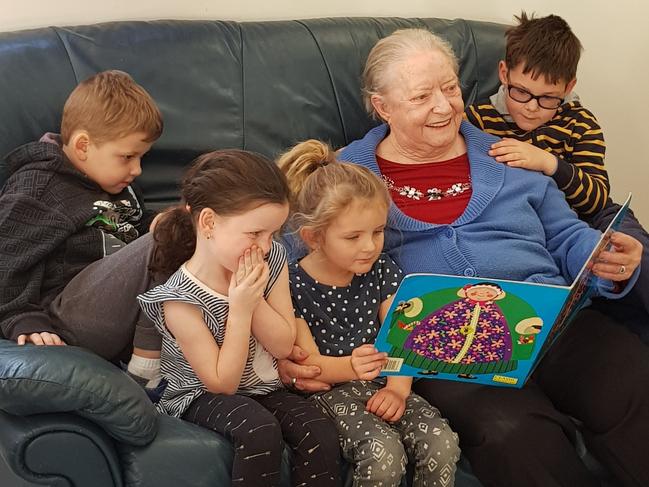 Barbara from the Peninsula Village aged care facility reads to (L-R) Beau Foster, Cailin Preston, Mali Bailey-Byford and Harry Karsten at Kids Club in Umina.