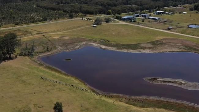 An aerial view of a human chain showing the width of the state government’s Coomera Connector along a dam on an Eagleby property which would be resumed.