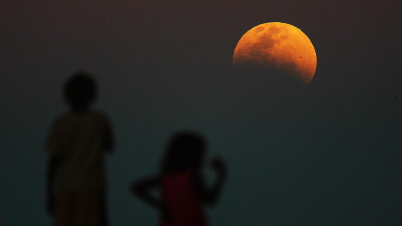 Lunar Eclipse. The Eclipse of the moon looking east from Kintore in the Northern Territory near the border of Western Australia. Picture also shows children from the Kintore School look out.
