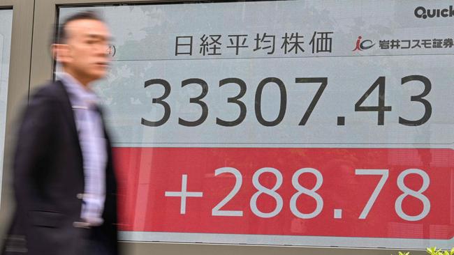 A man walks past an electronic board showing the numbers on the Tokyo Stock Exchange after the morning trading session ended, along a street in Tokyo on June 14, 2023. Tokyo shares opened higher on June 14 following US gains as investors awaited the US Federal Reserve's rate decision. The gains came after the Nikkei on June 13 powered to its best close since July 1990. (Photo by Richard A. Brooks / AFP)