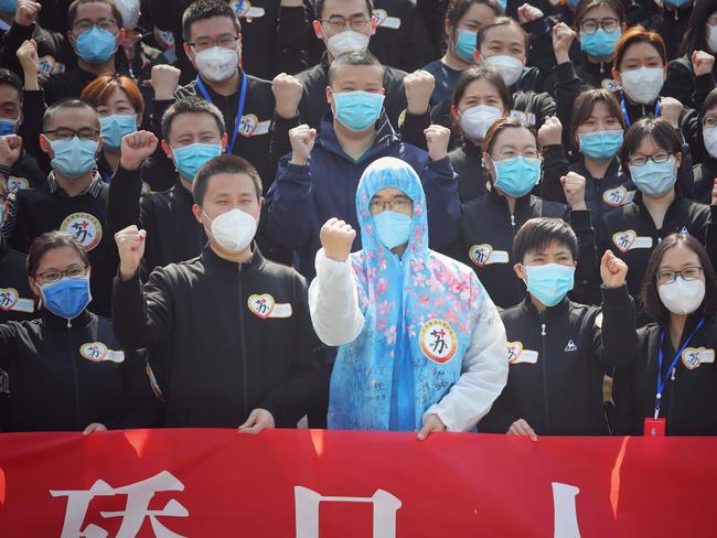 TOPSHOT - Members of a medical assistance team from Jiangsu province chant slogans at a ceremony marking their departure after helping with the COVID-19 coronavirus recovery effort, in Wuhan, in China's central Hubei province on March 19, 2020. - Medical teams from across China began leaving Wuhan this week after the number of new coronavirus infections dropped. China on March 19 reported no new domestic cases of the coronavirus for the first time since it started recording them in January, but recorded a spike in infections from abroad. (Photo by STR / AFP) / China OUT