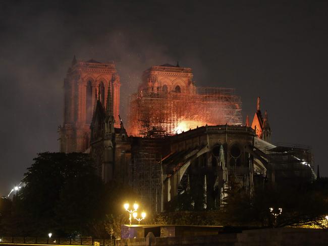 Flames are seen through the scaffolding as they engulf the roof of the Notre-Dame Cathedral in Paris on April 15, 2019. - A colossal fire swept through the famed Notre-Dame Cathedral in central Paris on April 15, 2019, causing a spire to collapse and raising fears over the future of the nearly millenium old building and its precious artworks. The fire, which began in the early evening, sent flames and huge clouds of grey smoke billowing into the Paris sky as stunned Parisians and tourists watched on in sheer horror. (Photo by ludovic MARIN / AFP)