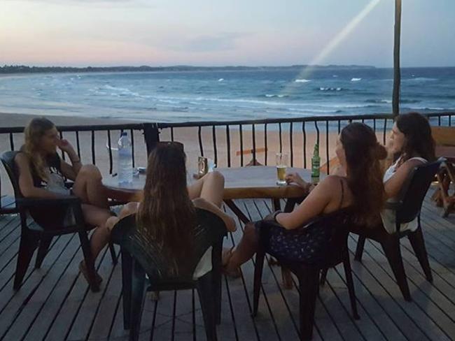 Elly Warren, left, relaxes with friends in Tofo in a photo taken on the night she died. It is the last image her parents have of their daughter alive. Picture: Supplied