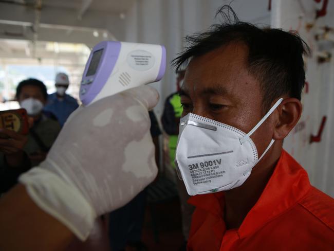 A worker gets his temperature checked on-board a ship that has arriving from China at the Panjang port in Lampung. Picture: AFP