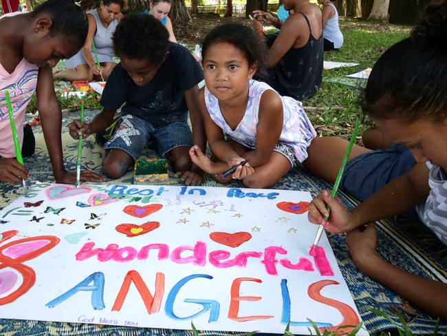 Angel Jacob, 11, and children paint messages under the trees in Murray Street Park, Cairns.