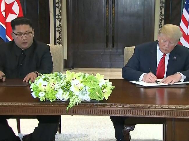 US President Donald Trump signs an agreement with North Korean leader Kim Jong-un after their meeting.