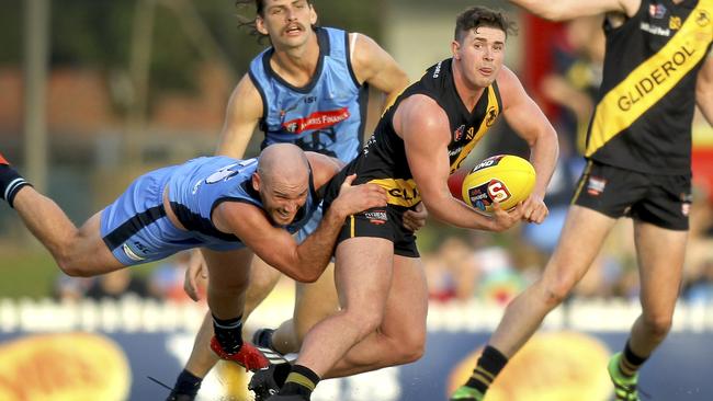 Brad McCarthy dishes out a handball under pressure from Sturt’s Zane Kirkwood. Picture: Dean Martin.