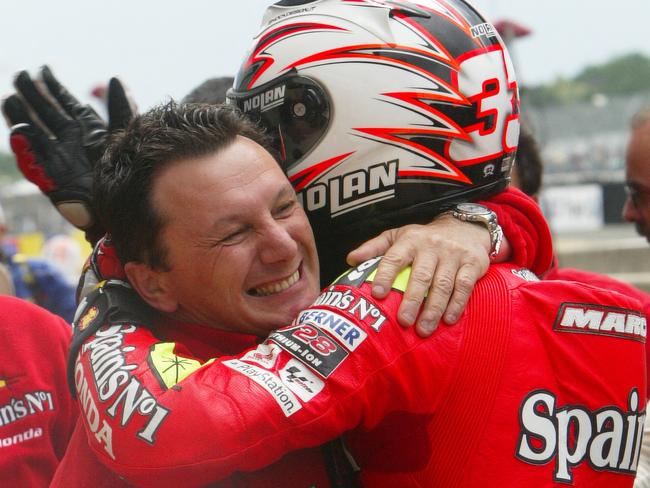 (FILES) In this file photo taken on May 21, 2006 Italy's Marco Melandri (R) is congratulated by his manager Fausto Gresini after winning the French MotoGP Grand Prix, at the Le Mans racetrack, western France. - Italian Fausto Gresini, a double 125cc world champion and MotoGP team owner, has died from the coronavirus aged 60, his team announced on February 23, 2021. (Photo by JEAN-FRANCOIS MONIER / AFP)