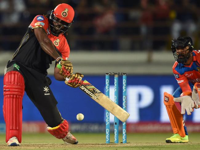 Royal Challengers Bangalore cricketer Chris Gayle (L) watched by Gujarat Lions wicketeeper Dinesh Karthik plays a shot during the 2017 Indian Premier League(IPL) Twenty20 cricket match between Gujarat Lions and Royal Challengers Bangalore at the Saurashtra Cricket Association Stadium in Rajkot on April 18, 2017.   GETTY OUT / ----IMAGE RESTRICTED TO EDITORIAL USE - STRICTLY NO COMMERCIAL USE----- / AFP PHOTO / INDRANIL MUKHERJEE / ----IMAGE RESTRICTED TO EDITORIAL USE - STRICTLY NO COMMERCIAL USE----- / GETTYOUT