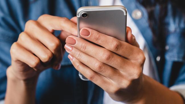 Cropped shot of an african-american young woman using smart phone at home.Smiling african american woman using smartphone at home, messaging or browsing social networks while relaxing on couch