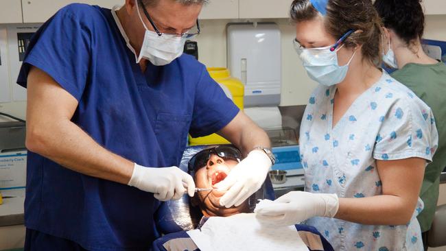 Dr. Daryl Holmes (left), seen working on a patient, believes the goodwill writedown at Smiles is hard to justify.