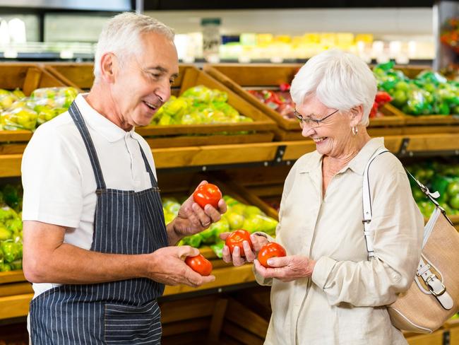 senior workers generic, older employees: Senior customer and worker discussing vegetables in supermarket