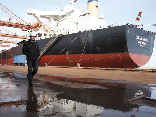 A man walks near a bulk carrier cargo ship docked at an iron-ore transfer and storage center operated by the Shanghai International Port Group in Shanghai, China on 26 January 2010.   Xxx at the Yangshan deep-water port in Shanghai, China, on Tuesday, Jan. 26, 2010. Photographer: Qilai Shen/Bloomberg