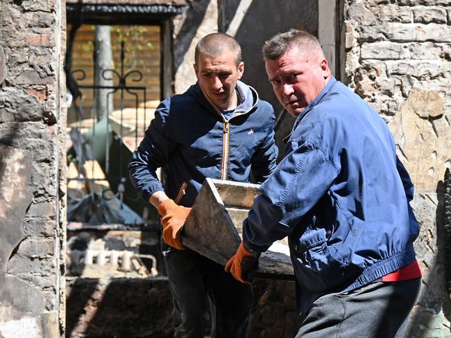Museum workers carry part of a surviving exhibit from the destroyed building of the Hryhoriy Skovoroda National Literary Memorial Museum. Picture: AFP