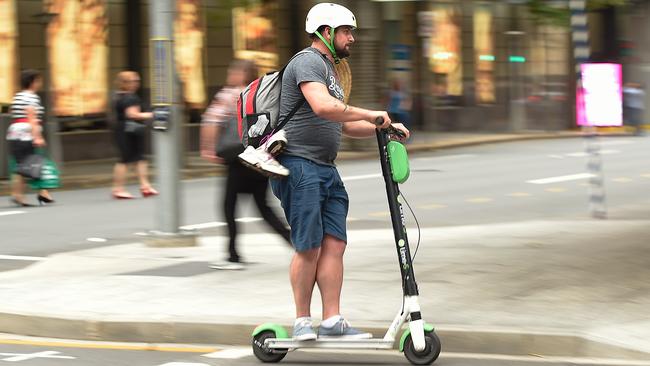 A Lime user crosses the street on a scooter in the Brisbane CBD. AAP Image/Albert Perez