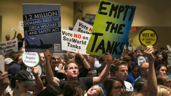 Animal rights activist Kirby Kotler, with his daughter, Kirra, 12, from Malibu, hold up signs as opponents and supporters fill the room during a California Coastal Commission meeting in California in 2015.