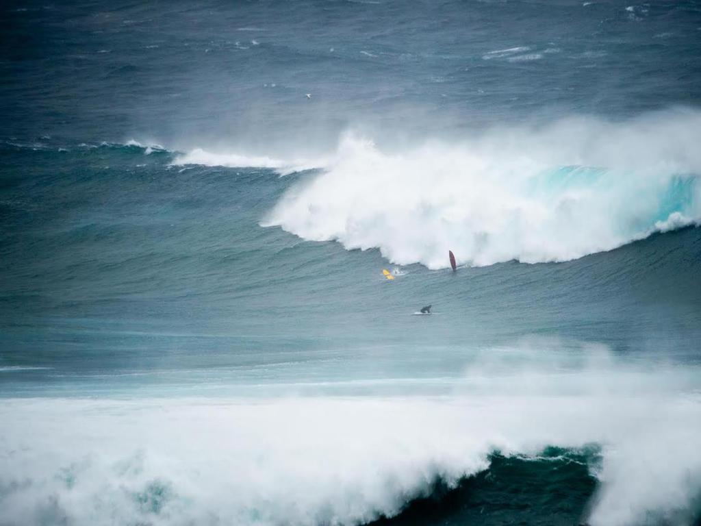 Surfers on longboards struggle in the massive swells at Wedding Cake Island Coogee. Picture: Glenn Duffus