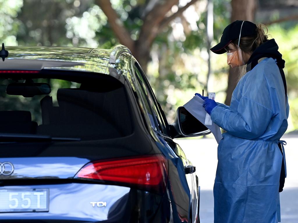 Health workers dressed in Personal Protection Equipment (PPE) wait for patients to arrive at the Willoughby Leisure Centre Drive-through Covid-19 testing clinic in Sydney.