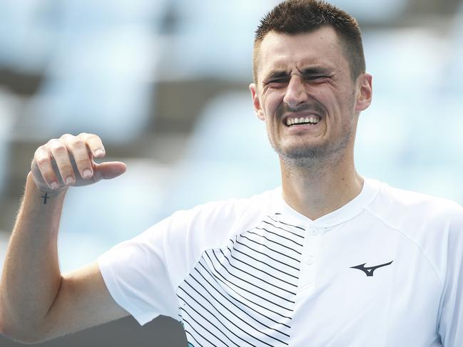 Bernard Tomic grimaces as he lifts his injured hand during his match against Denis Kudla.