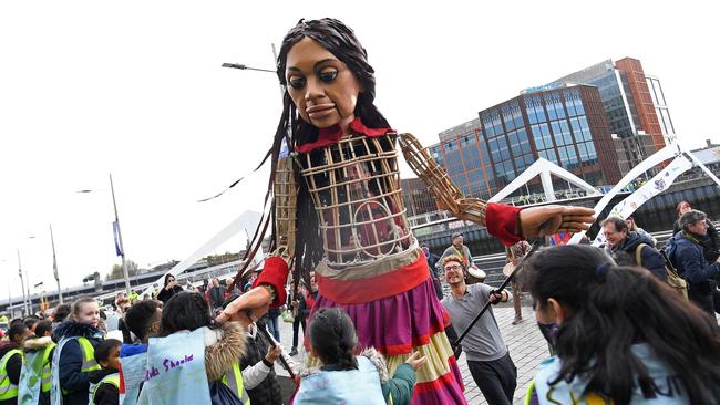 Little Amal, a giant puppet depicting a Syrian refugee girl, is greeted by local schoolchildren, on the banks of the River Clyde, in Glasgow during the COP26 UN Climate Change Conference. Picture: Paul Ellis / AFP