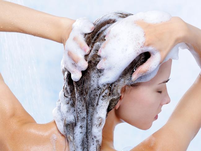 Close-up portrait of young pretty woman taking a shower and washing her hair.