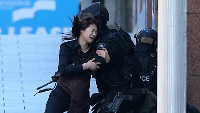 A tactical officer grabs a hostage as she bursts from the Lindt cafe during the siege. Picture: Adam Taylor