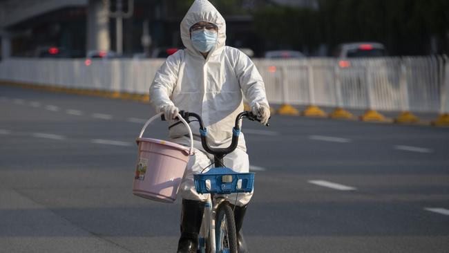 A resident wearing mask and suit against the coronavirus cycles in Wuhan in central China's Hubei province on Sunday. Picture: Ng Han Guan/AP