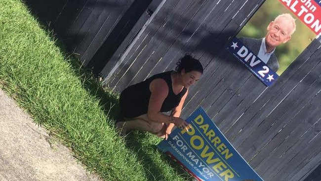 Megan Sinnamon picks up one of the dumped Darren Power signs from her front footpath.