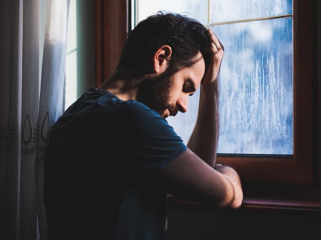 Young sad mad sitting by the window in regret istock RendezView