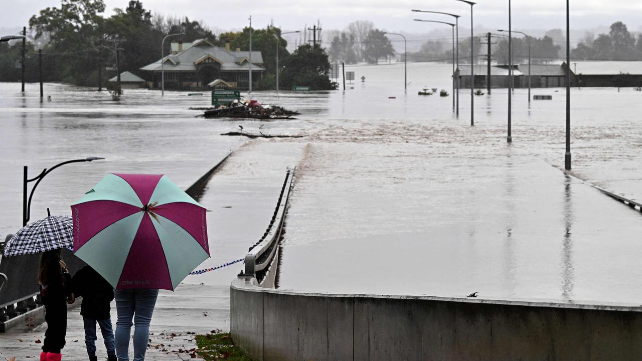 Residents look out toward flooded buildings next to the Windsor Bridge along the overflowing Hawkesbury River. Picture: SAEED KHAN/AFP