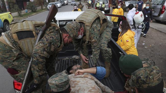 Soldiers help a city worker who fainted at an army soup kitchen for people facing hardship because of lost income due to the new coronavirus pandemic, in Maipu, on the outskirts of Santiago, Chile. Picture: AP