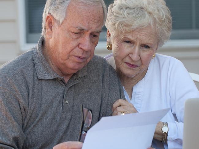 Senior couple working on home / personal finance using laptop with concerned expression; retirement money generic