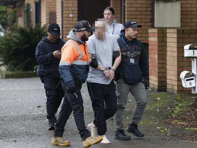 Officers lead a suspect away from a townhouse in the Blacktown area. Picture: Richard Dobson