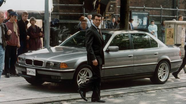 James Bond actor Pierce Brosnan standing in front of BMW 7-Series sedan in 1997 film "Tomorrow Never Dies".